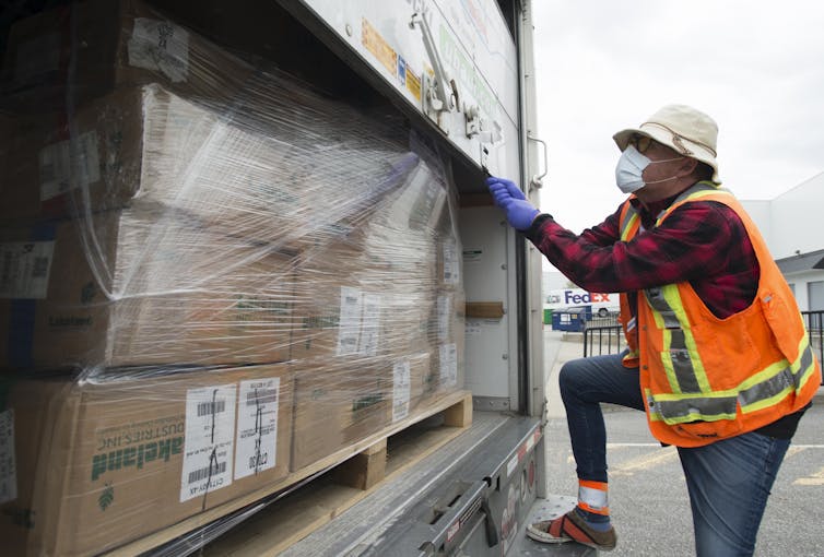 A driver secures a load of personal protective equipment in a truck