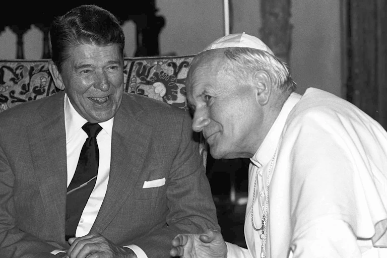 President Ronald Reagan sits and chats with Pope John Paul II.
