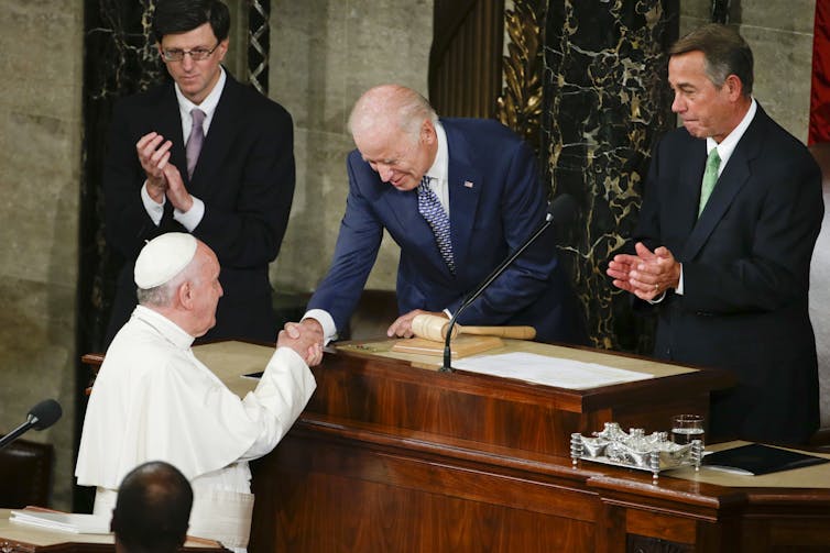 Pope Francis reaches up to shake the hand of Joe Biden, then vice president, in Congress.