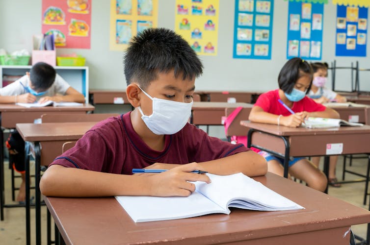 Students sit at desks to do schoolwork