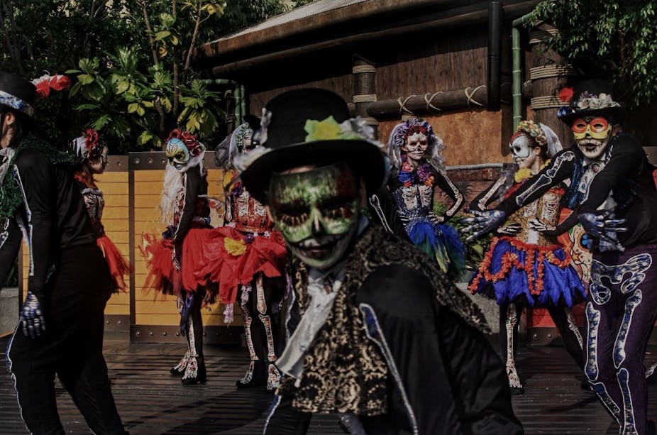 People seen dancing while wearing Day of the Dead costumes.