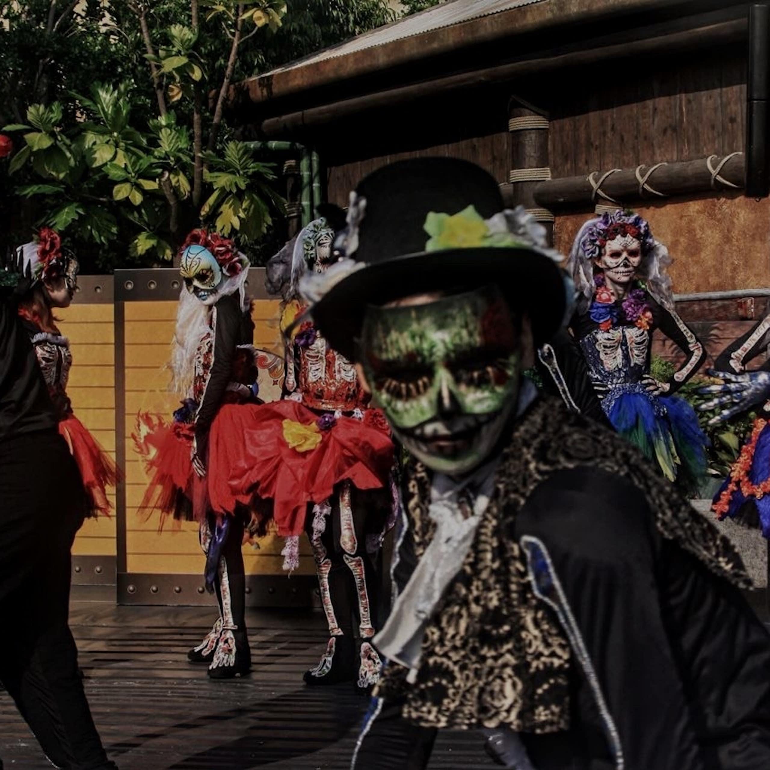 People seen dancing while wearing Day of the Dead costumes.