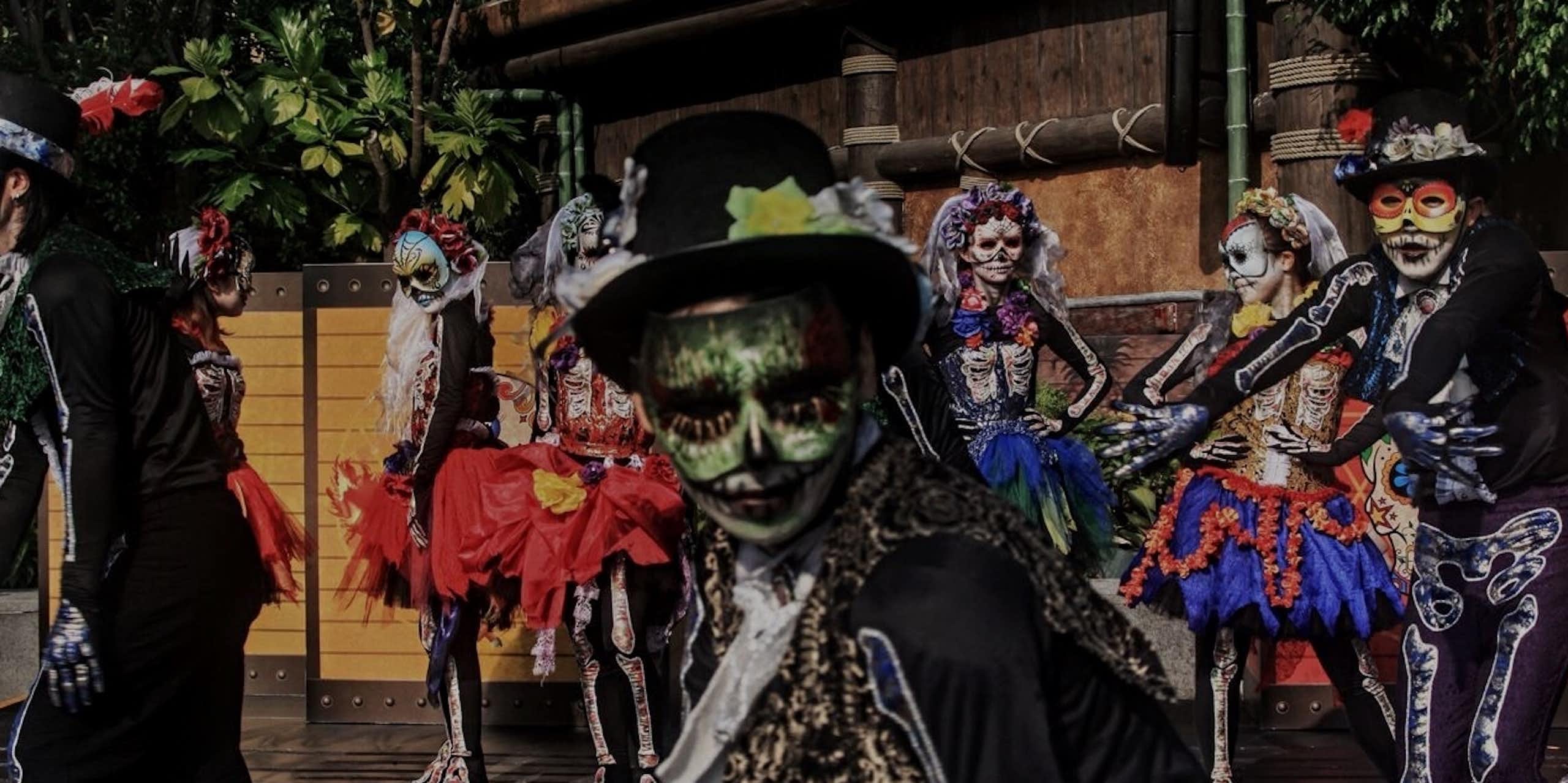 People seen dancing while wearing Day of the Dead costumes.