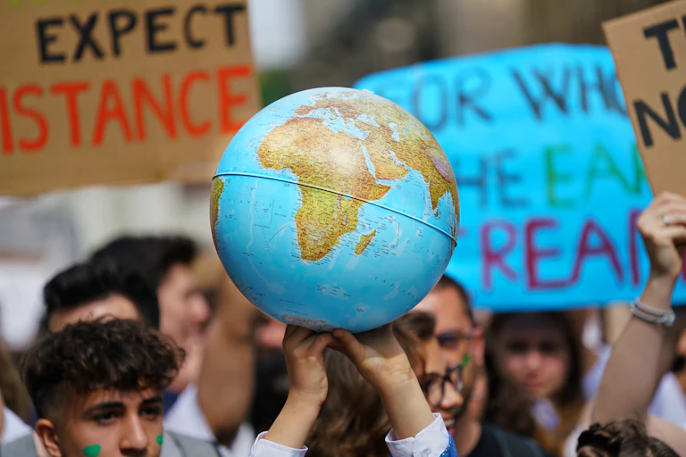 A crowd of young protesters hold a globe aloft.