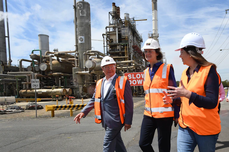 man and two women walk in front of industrial site