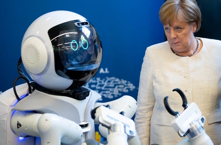 German Chancellor Angela Merkel looks at a a care robot as she visits the Munich School of Robotics and Machine Intelligence of Munich’s Technichal Univeristy