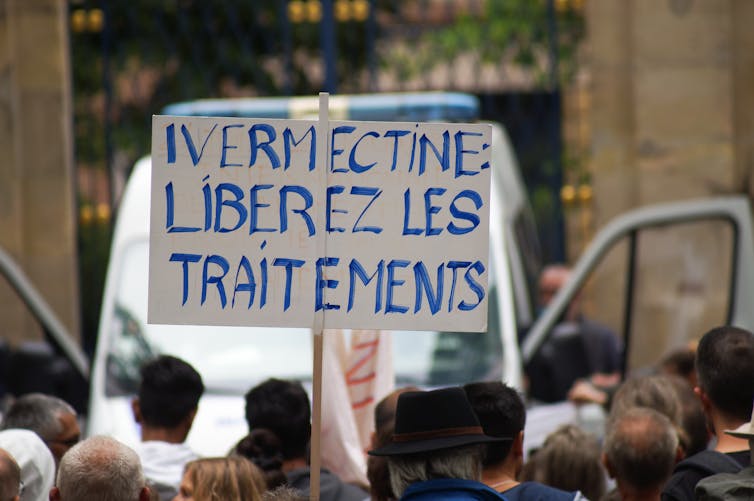 A french protester holding a placard that says 'Ivermectin: release the treatments'