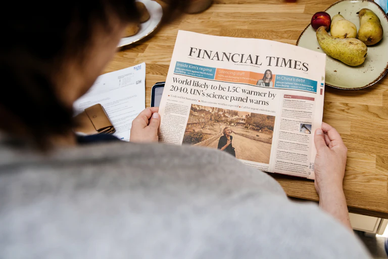 A person reads a headline about climate change in the Financial Times.