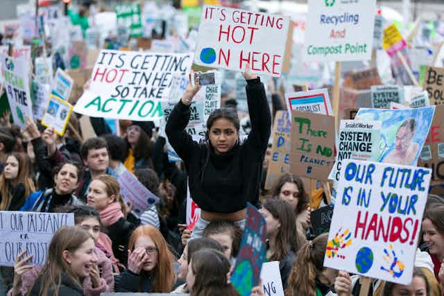 Girl on a march holds up 'it's getting hot on here' sign