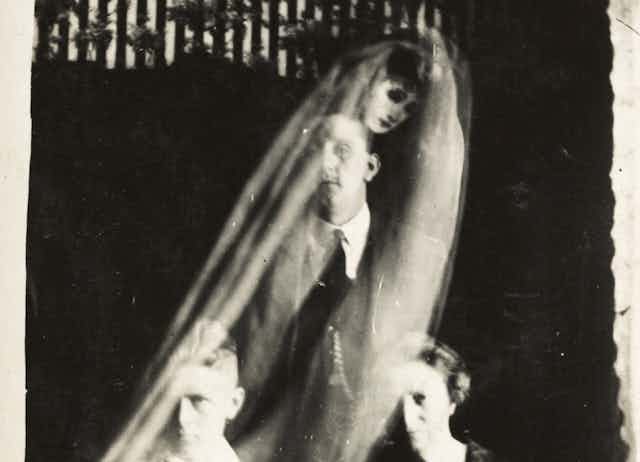 A semi-translucent image of a veiled woman seen behind a man.