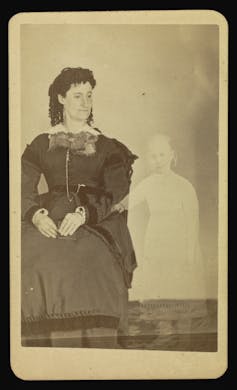 Black and white photo of a woman seated next to a semi-translucent child.
