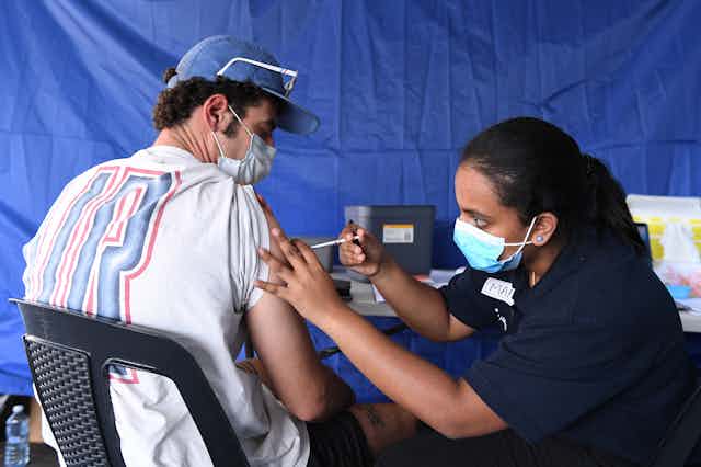 Health worker giving person a COVID vaccine dose