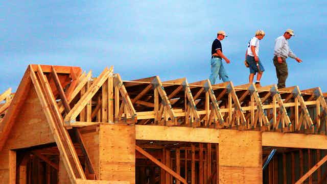 Construction workers on roof of partially constructed house