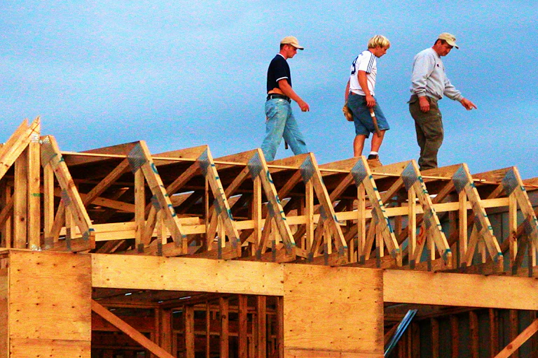 Construction workers on roof of partially constructed house