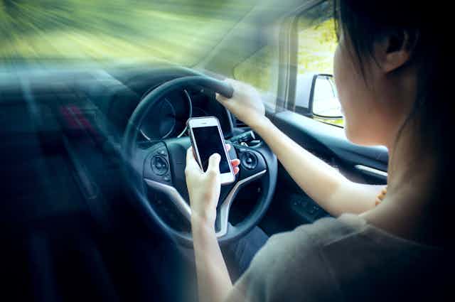 Young woman uses mobile phone while driving