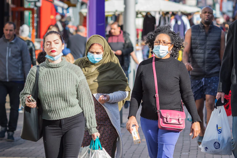 People walking down the street wearing masks