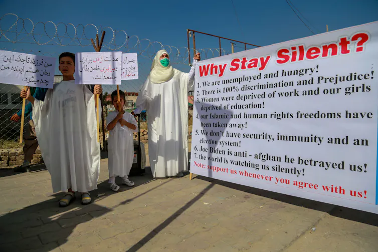 An Afghan teacher and her family, wearing traditional burial shrouds, protesting about oppression under the Taliban