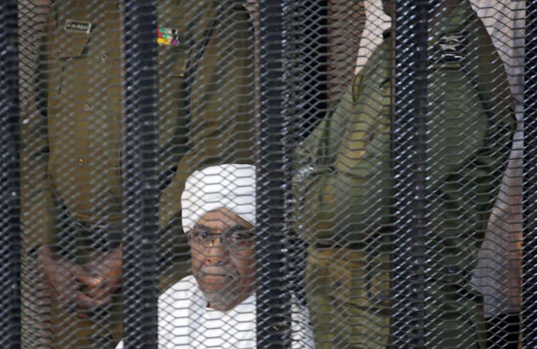 Omar Hassan al-Bashir looks out from inside the accused cage, during his trial in Khartoum, Sudan, August 2019.