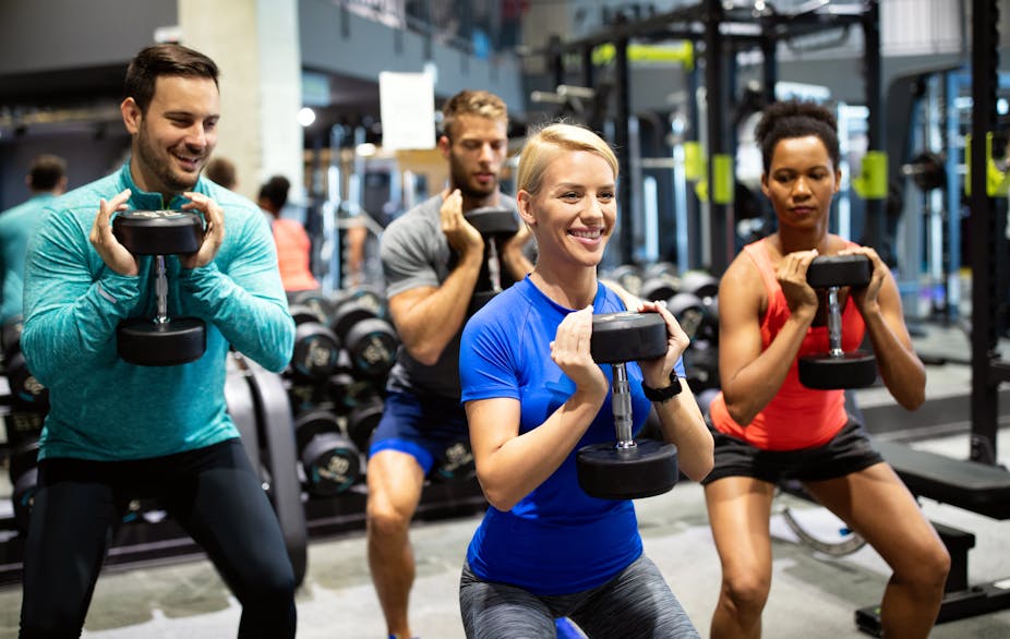 A group of four people exercising together with dumbbells. 