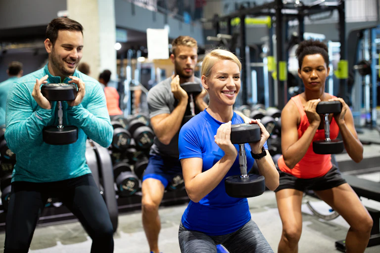 A group of four people exercising together with dumbbells.