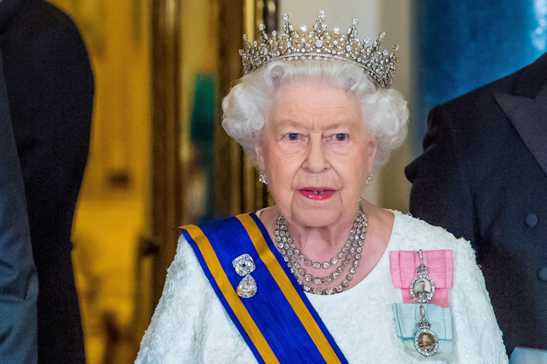 Queen Elizabeth II wearing a crown, sash and medals.