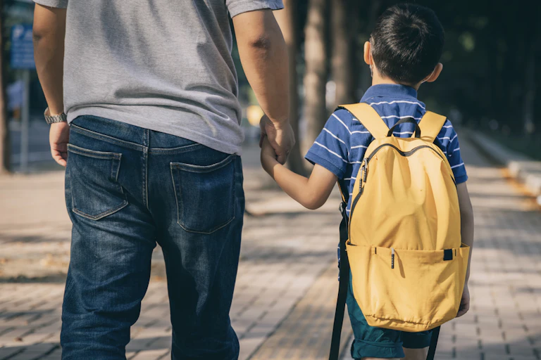 Father and son holding hands on the way to school.