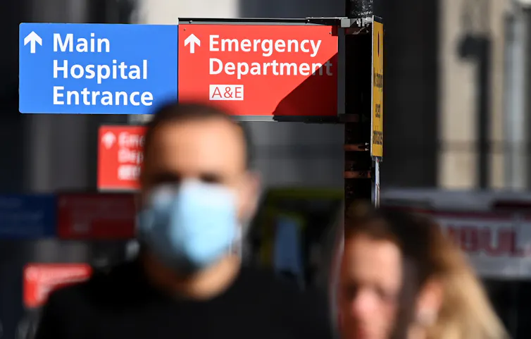 People walking in front of hospital signs