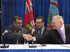 Doug Ford shakes hands with two First Nations chiefs.