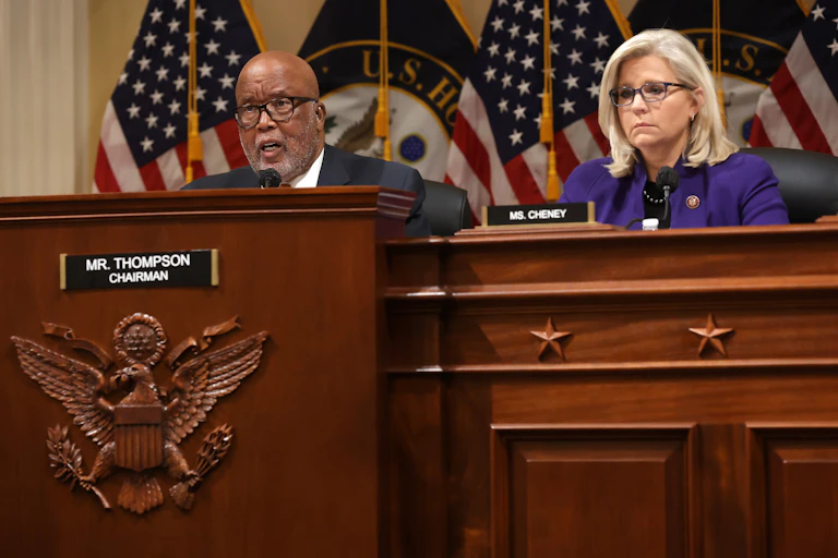 Sitting behind a large wooden committee desk are US Reps. Bennie Thompson and Liz Cheney.