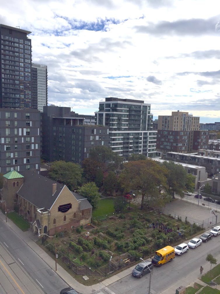 Urban streetscape shot from above: a garden, a basketball court, a church and taller buildings.