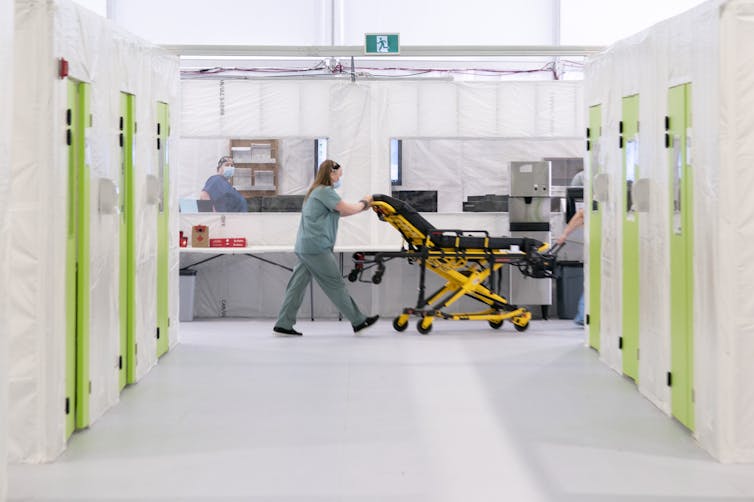 A health-care worker pushing a gurney at the end of a hallway.