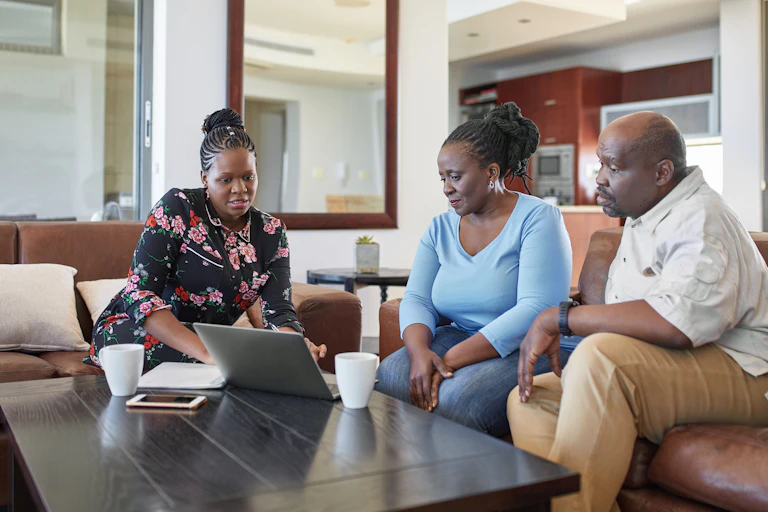 Mature people receiving advice by a younger women on a computer.