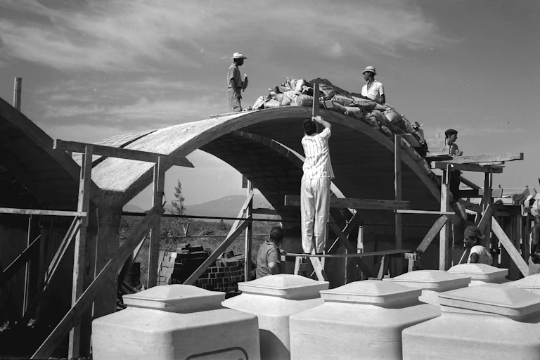 Men labor on a vaulted structure.