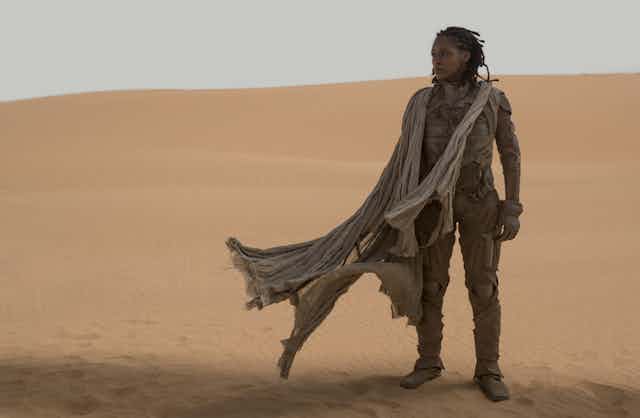 Woman stands in a desert landscape. 