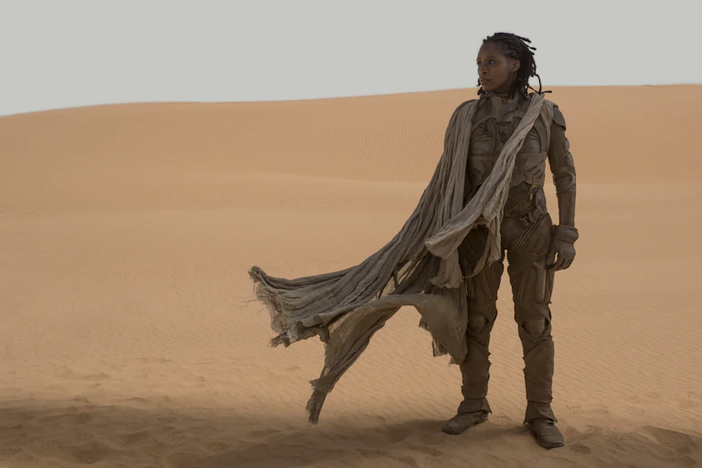 Woman stands in a desert landscape.