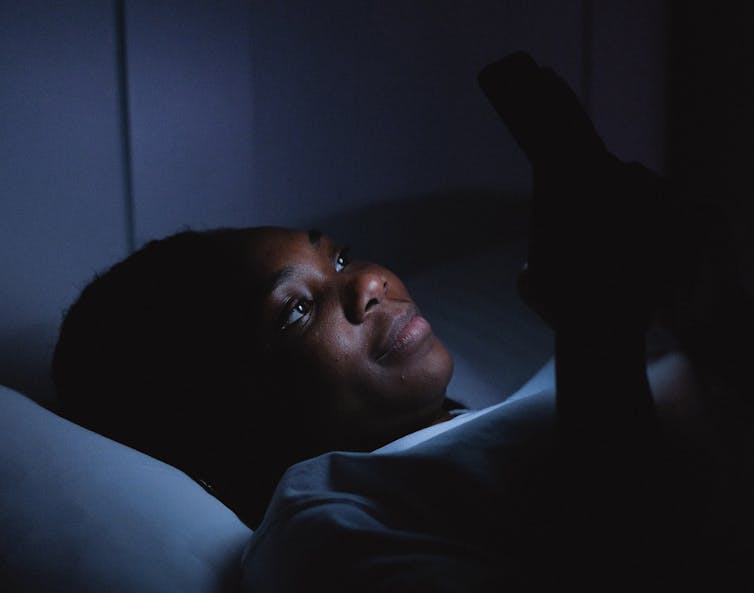 Une jeune femme consulte son portable en pleine nuit