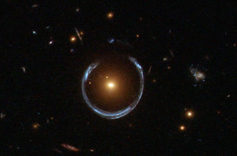 A blue horseshoe of light surrounds an orange galaxy.