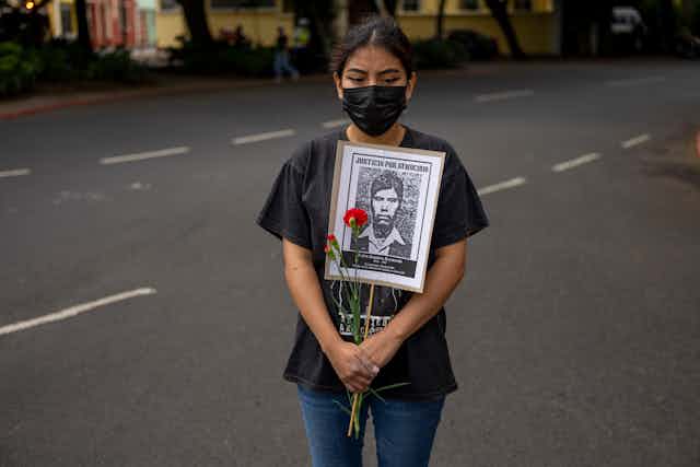 A woman holds a portrait of a man who was allegedly disappeared by the Guatemalan Army