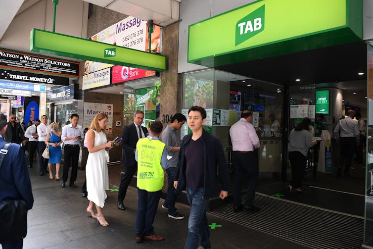 Punters line up to place a bet at the TAB.