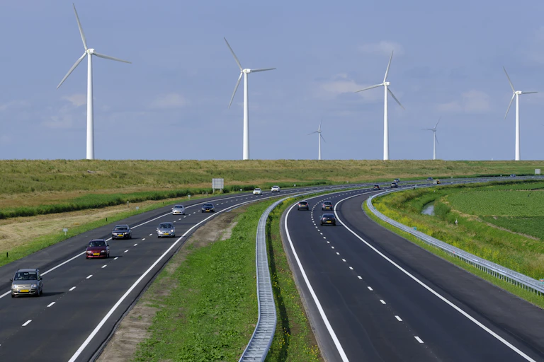Cars travelling along a motorway, with wind turbines in the background