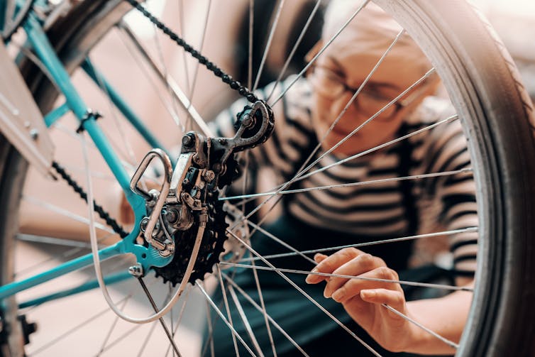 A woman repairs a bike.
