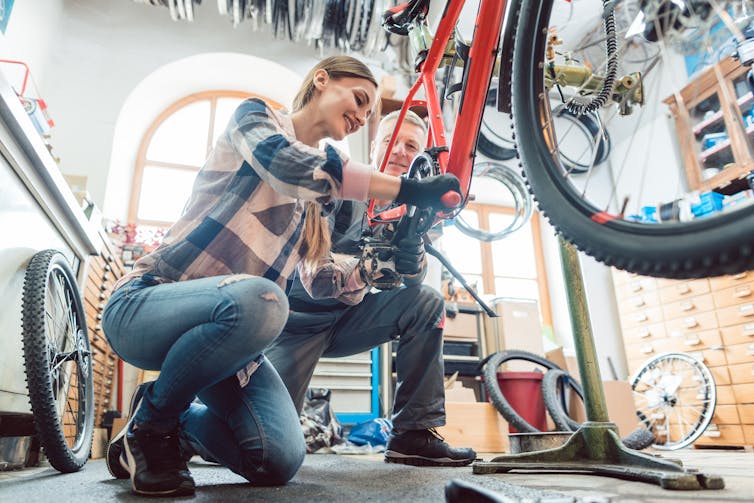 A woman and a man work together on a bike.