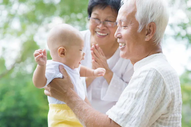 Grandparents hug a baby.