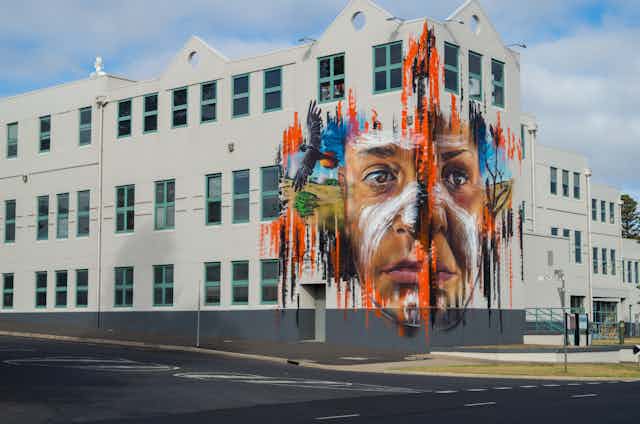 A mural of an Aboriginal young person on the corner of a building.