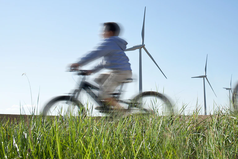A man and child cycle past wind turbines.