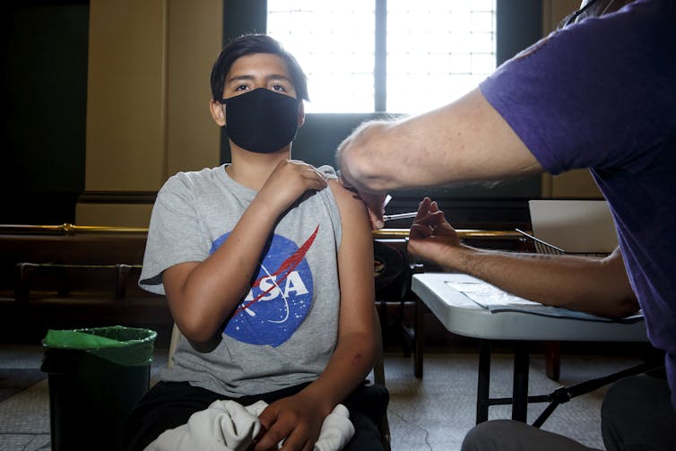 Un garçon portant un masque reçoit une injection