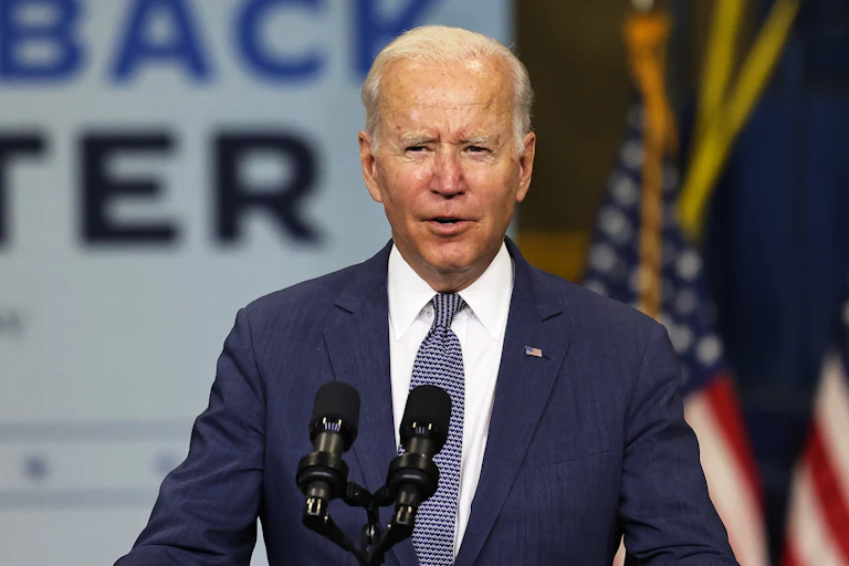 Joe Biden standing in front of a sign with his climate slogan: Build Back Better