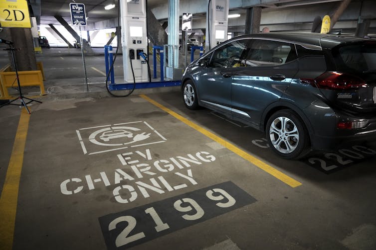 An electric vehicle charging next to an EVs-only parking space