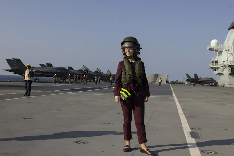 Liz Truss standing on the deck of an aircraft carrier.