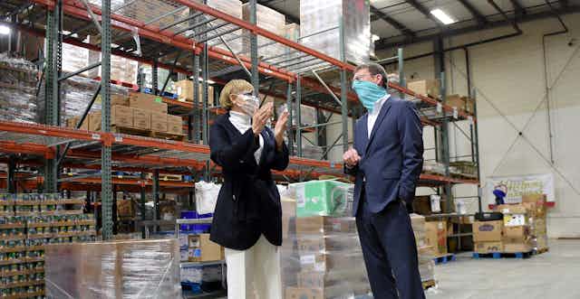 Two people in suits speak to each other in a food warehouse